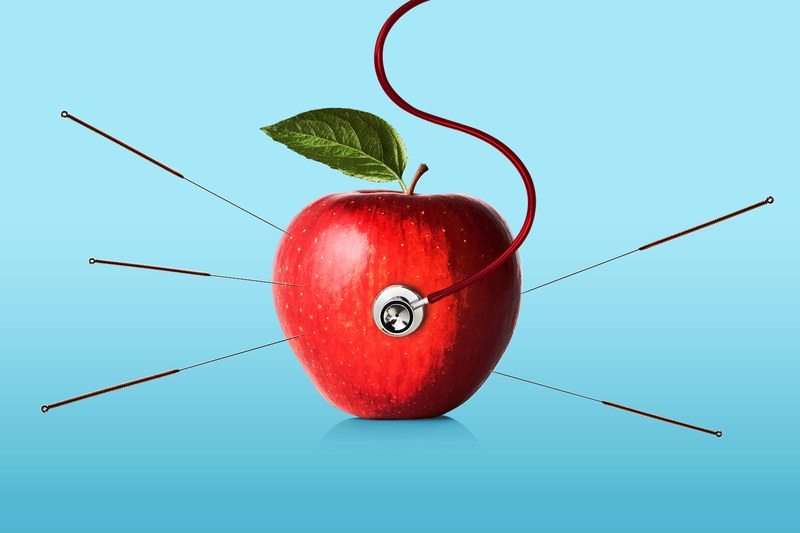 Red apple with acupuncture needles and a stethoscope