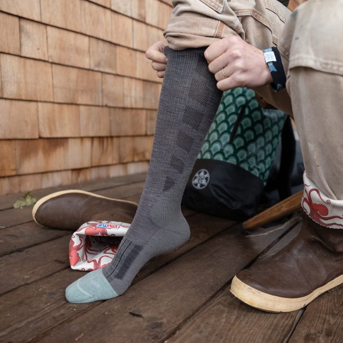 Person on deck pulling on Emma Claire works socks and rubber boots. See those breathable mesh vents on the sock?