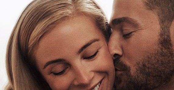 Man kissing the cheek of a smiling woman