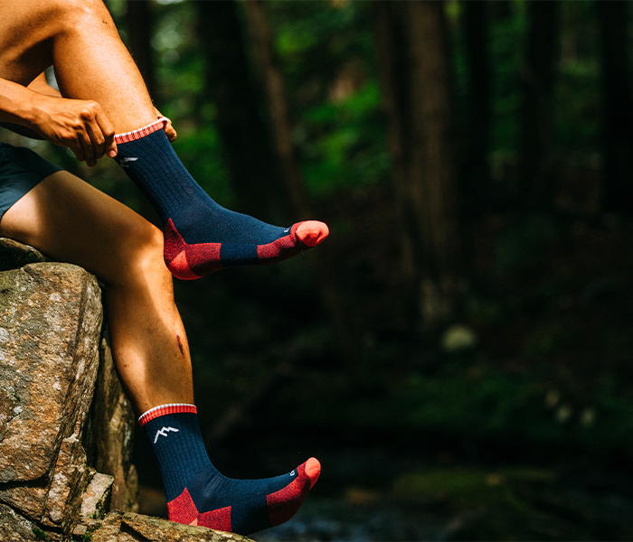 Some guy in the forest pulls up fresh hiker crew socks.