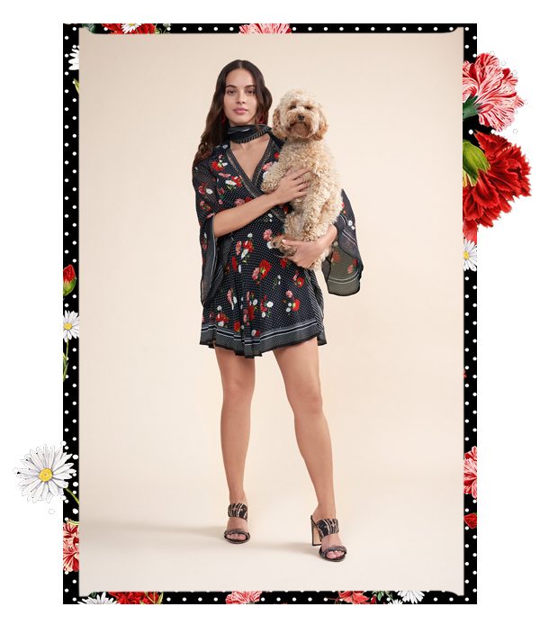 Model wearing floral and polka dot wrap dress holding dog