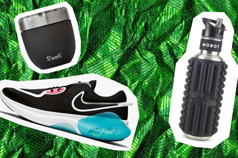 A swell mug, a nike joyride sneaker, and a foam roller on a green wrapping paper background