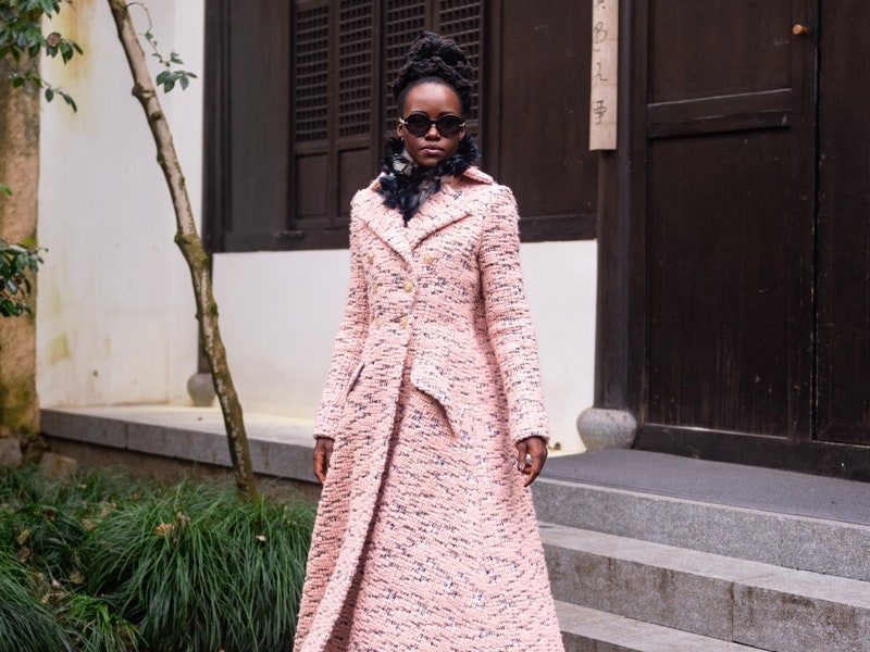 Image may contain: Lupita Nyong'o, Person, Black Hair, Hair, Accessories, Glasses, Adult, Clothing, and Coat