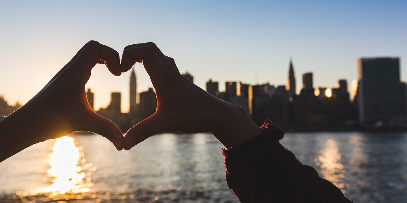 Heart shaped hands at sunset overlooking New York skyline