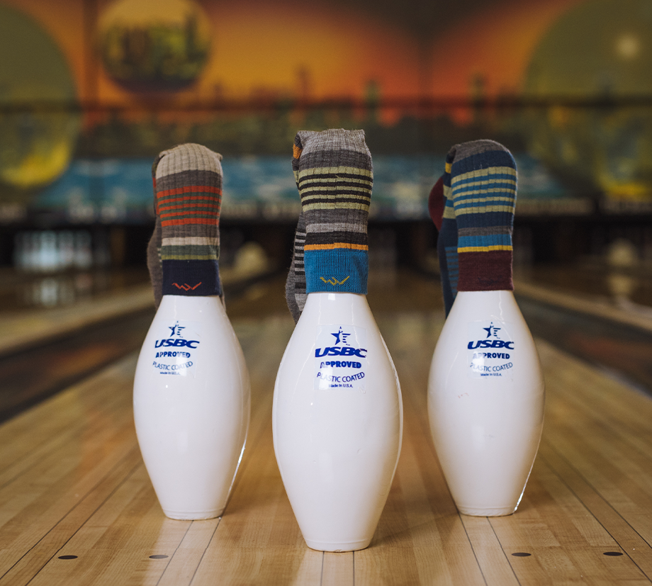 Three bowling pins, full of Dad energy, each with striped socks on its top.