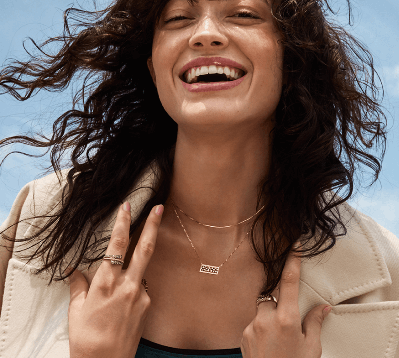 A woman happily poses, showcasing her new beautiful Diamond Jewelry - Necklaces and Rings.