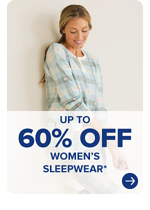 A woman in a plaid pajama shirt. Up to 60% off women's sleepwear.