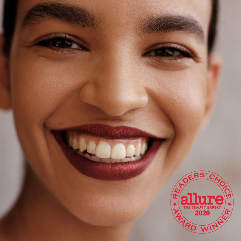 black woman with metallic red lipstick smiling and the allure readers choice awards seal