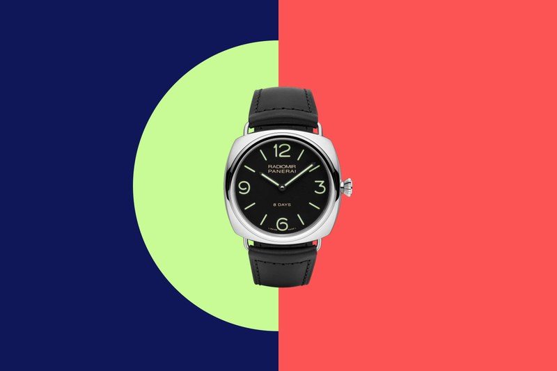 A watch with a black leather band on a blue green and pink color-blocked background