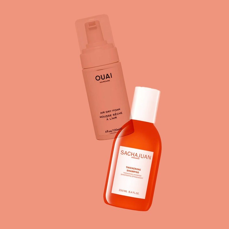 Hair products from Sachajuan and Ouai scattered on a peach-colored background