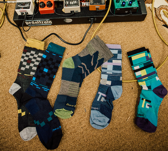 This image of five beautifully colorful socks sitting next to electric guitar pedals speaks to the loud nature yet beautiful sound of the comfort, durability and fit of our socks.