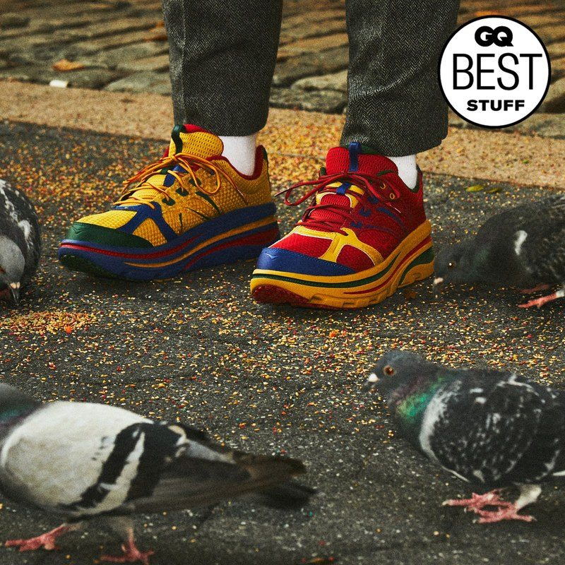 A person wearing multicolored sneakers while pigeons eat food from the ground around them
