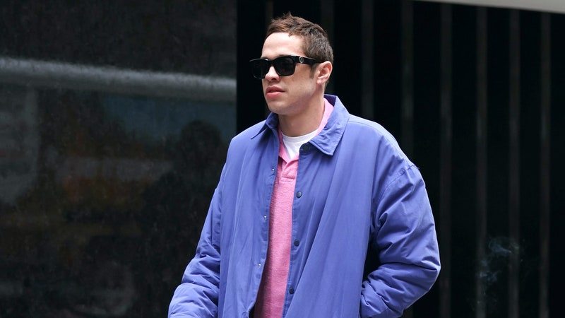 Pete Davidson is seen on the set of %22Bupkis%22 in New York City wearing a pink shirt, purple jacket, and blue pants
