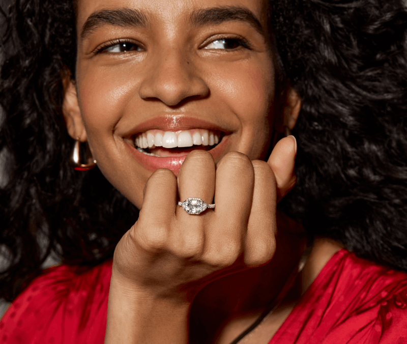 A smiling woman holds up her left hand in a fist, showing off her diamond ring