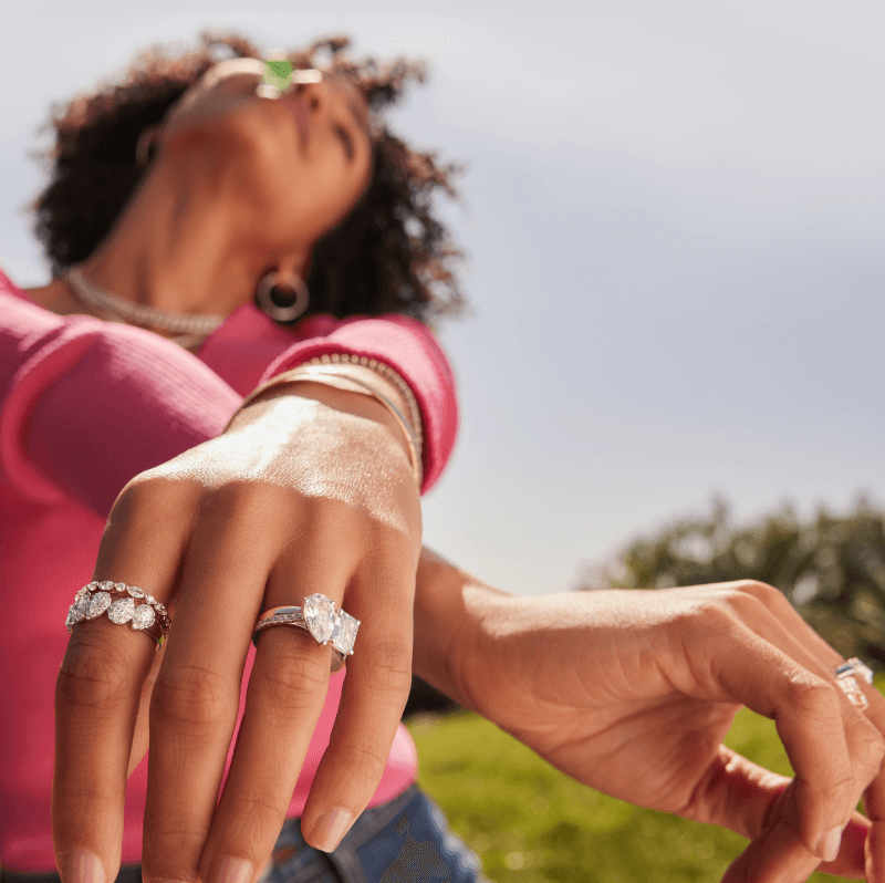 A woman poses in the, with her outstreched arms adorned with golden bracelets and stunning diamond rings.