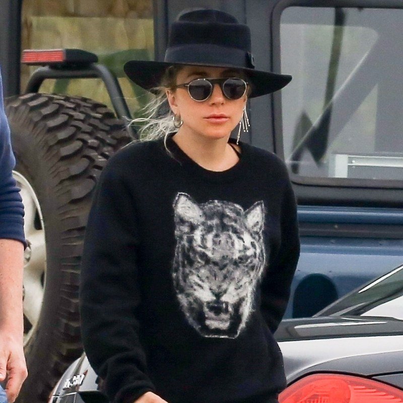 Lady Gaga pairs rounded sunglasses with a black hat.