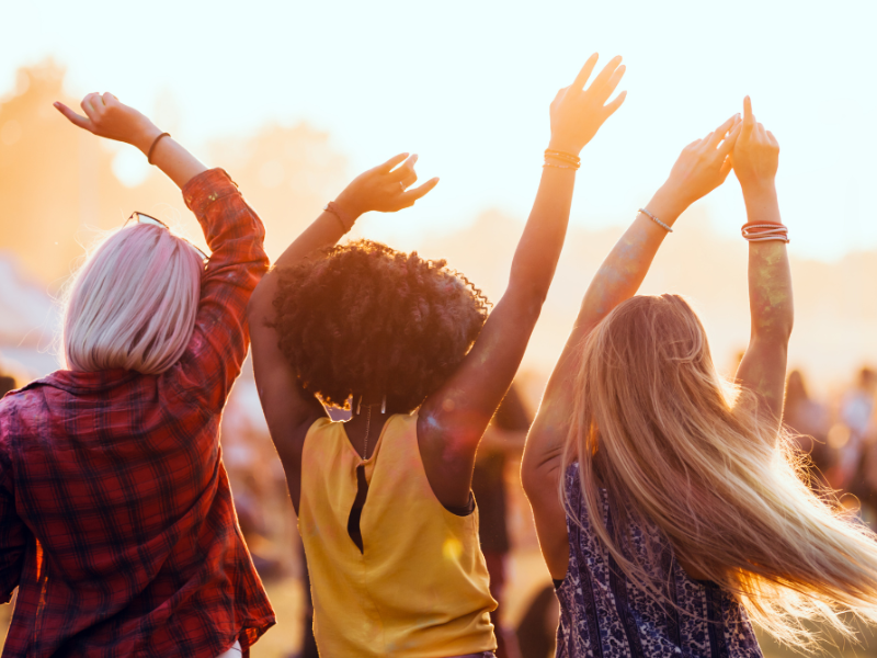 Three women dancing together at a festival.