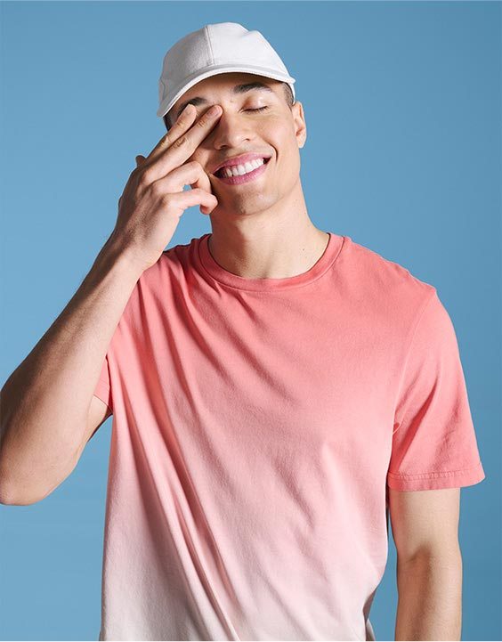 Man wearing coral ombré T-shirt and white baseball cap