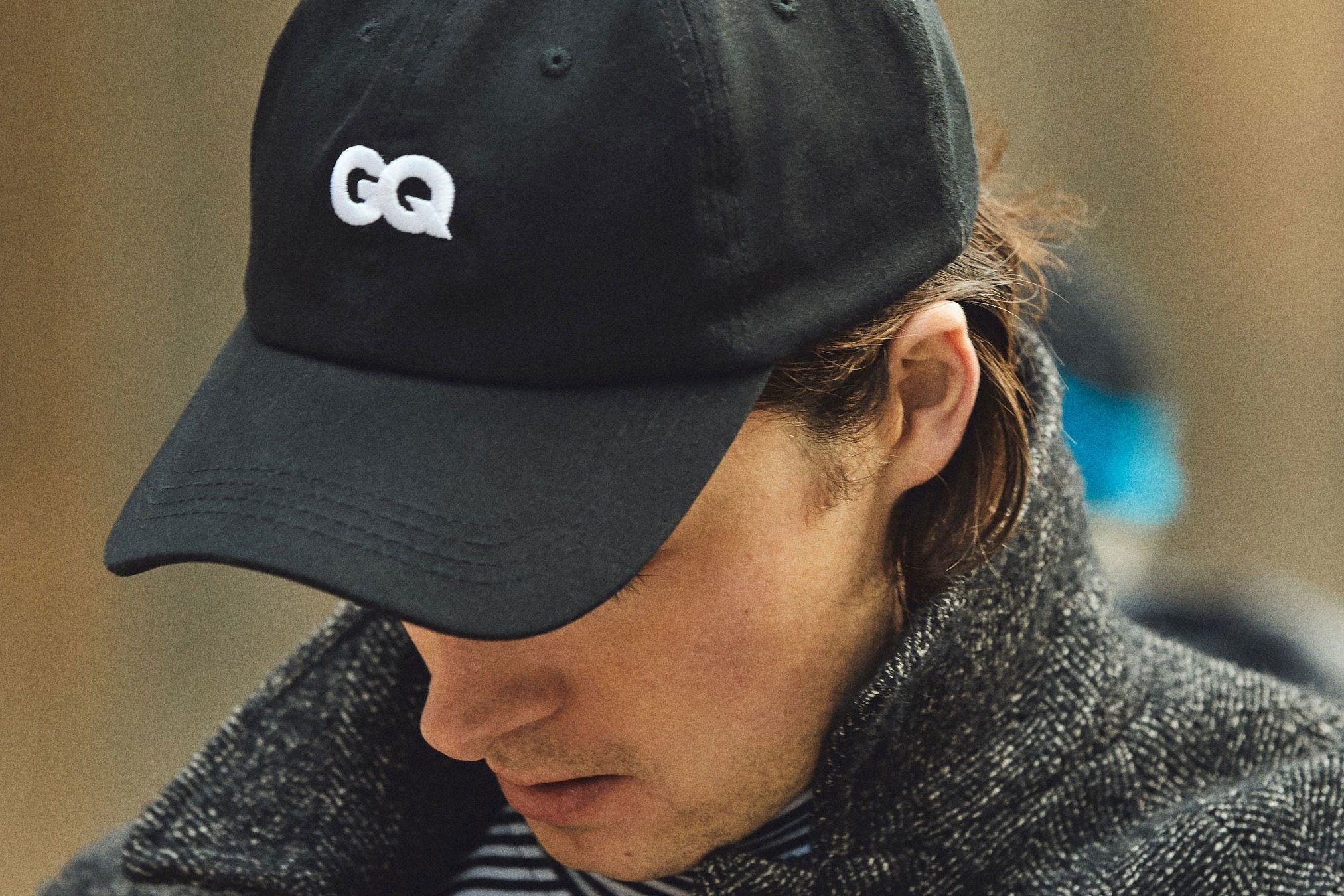 a black baseball cap with a white gq logo on the front and the phrase proud subscriber in white letters on the back rotating on a white background