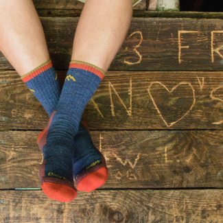 Check our Instagram for updates - a hiker wearing blue and orange 1466 socks in a cabin