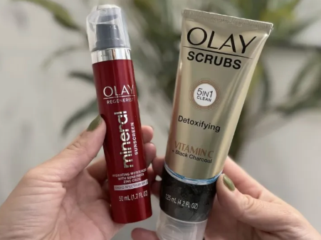 Hand holding Olay Mineral Sunscreen and Olay Detoxifying Face Scrub