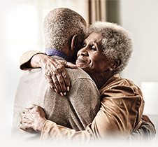 Image of an elderly man hugging and elderly woman