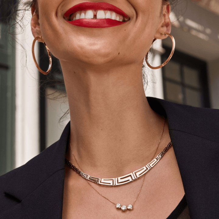 A woman is pictured smiling while her gold earrings and necklaces shine bright.