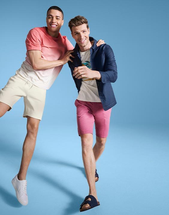 Man wearing coral ombré T-shirt and beige shorts and man wearing white T-shirt, navy overshirt and pink shorts