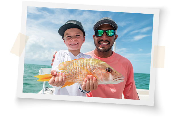 Father smiling and son smiling while holding a fish