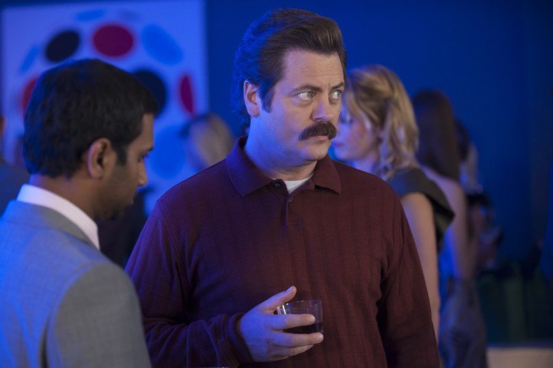 actor Nick Offerman as Ron Swanson in Parks and Recreation holding a glass of whiskey illuminated in blue light