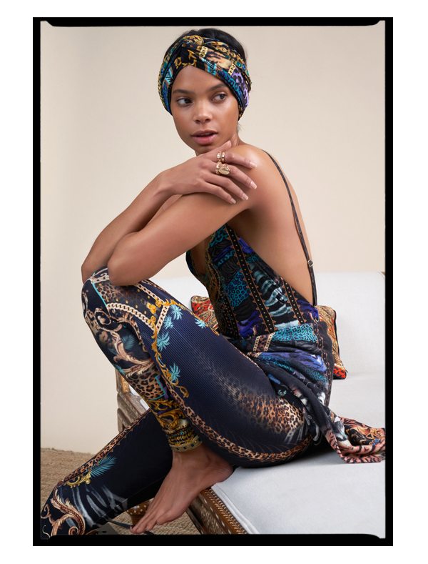 Model sitting on daybed wearing She's Got Grace Leggings and Low Back Bodysuit with Headband