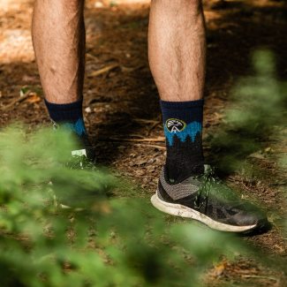 Shop Socks that conserve iconic trails - a hiker wearing Appalachian Trail Conservancy socks on a wooded trail