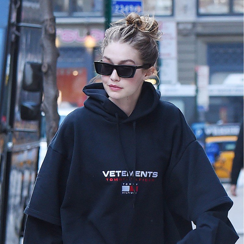 Gigi Hadid pairs a topknot with black sunglasses.