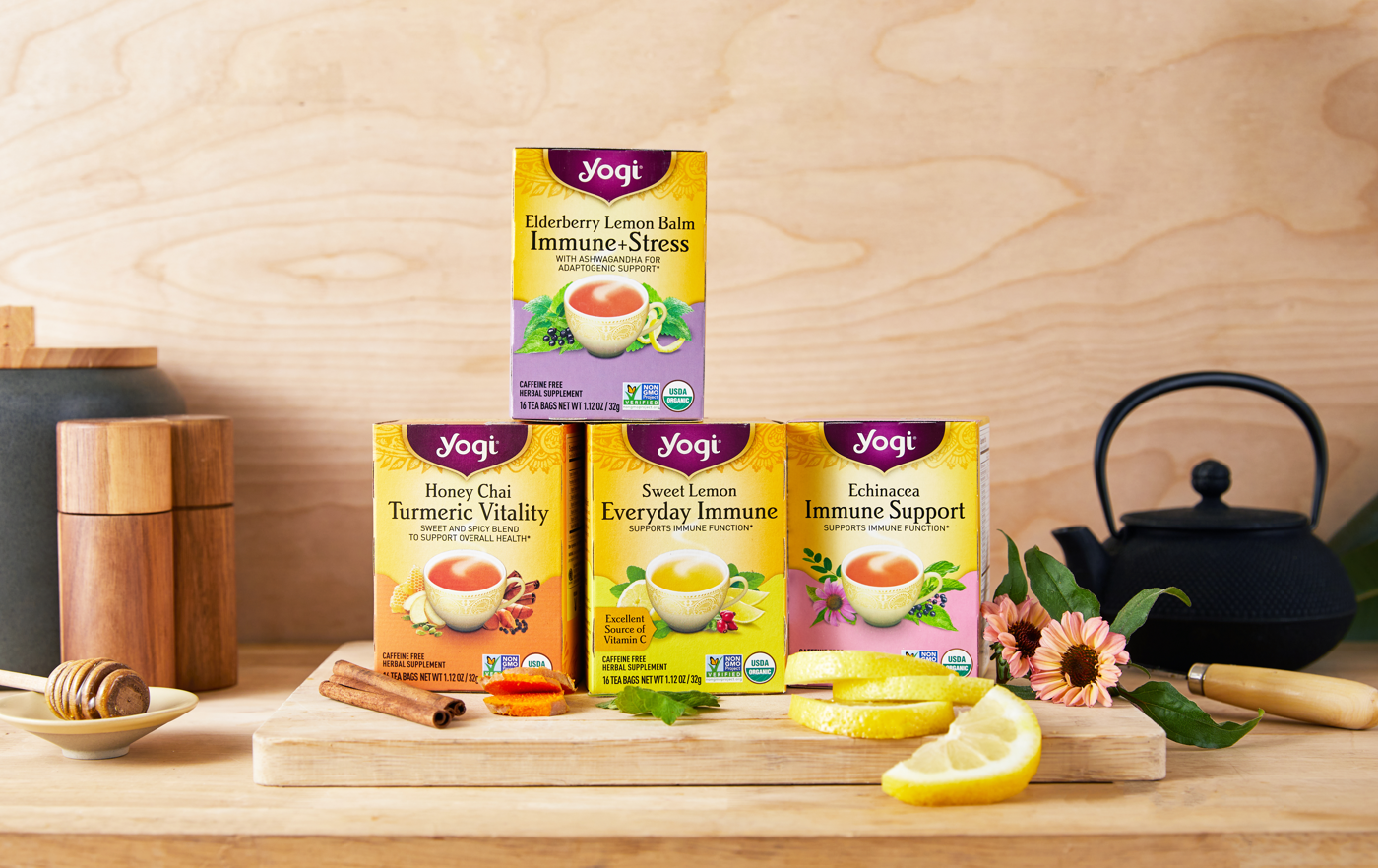 4 cartons of Yogi Immune Supporting teas sit on a kitchen counter next to fresh lemon, echinacea, and cinnamon