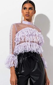 The AKIRA Label God Is A Woman Sheer Ruffle Blouse is a mesh based top complete with long sleeves, a high neck collar, ruffle detailing and mini pom pom trim outlining the piece.