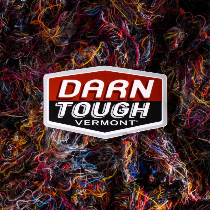 Learn more about Merino - the Darn Tough logo sits above a colorful jumble of tangled wool yarns