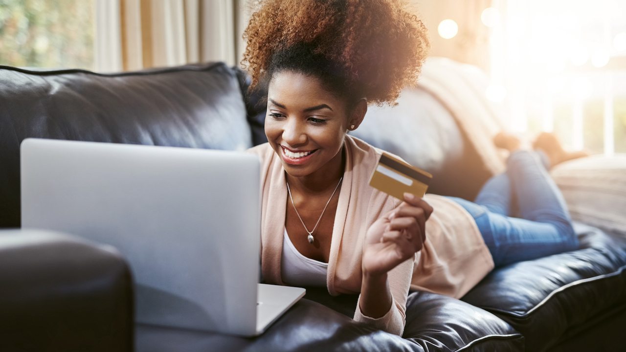 Woman holding credit card on couch
