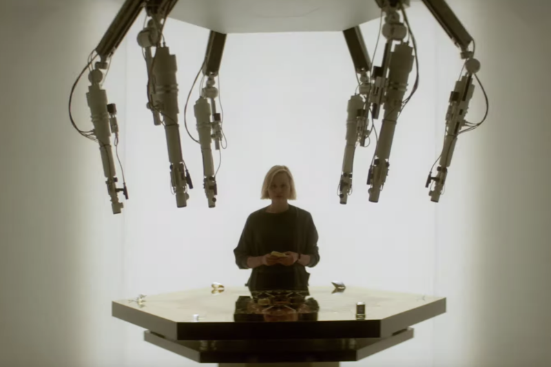 an image from the trailer from FX's new show Devs, in which a woman sits behind a table, and a metallic claw hangs above the table