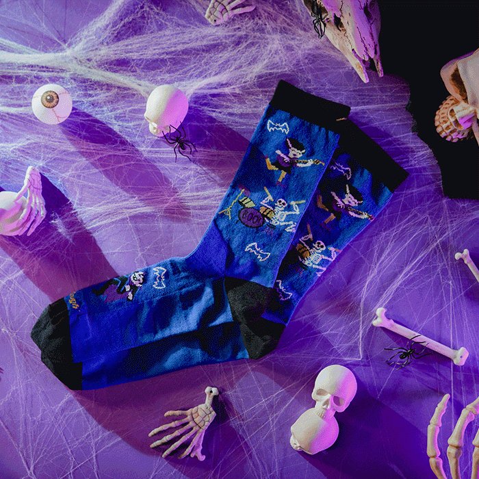 Shop Halloween socks - socks featuring skeletons in a rock band lay on a spider web surrounded by spooky items