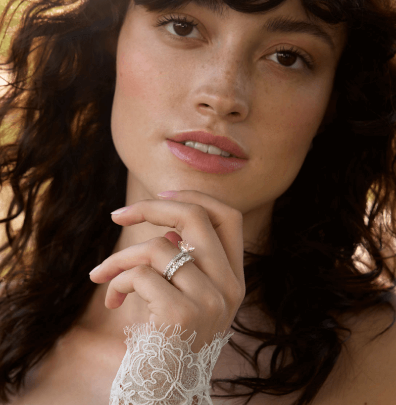 A bride poses, prominently featuring a beautiful bridal ring.