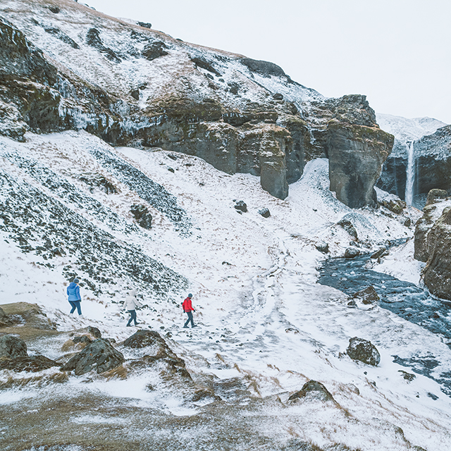 Three hikers exploring a snowy, craggy landscape. 
