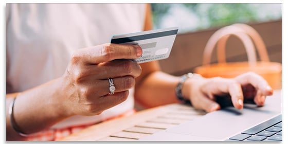 Woman using a credit card and a laptop.