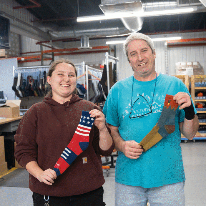 Darn Tough dads and their kids who work with them, both holding up their recommended socks for Father's Day gifts