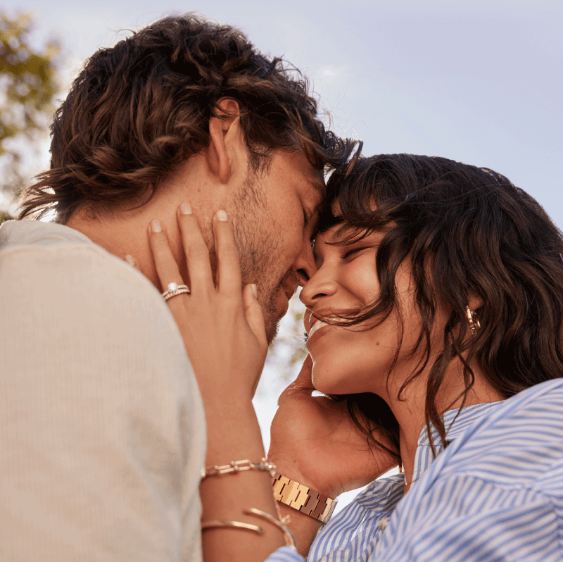 A couple sharing a warm embrace, wearing gold beautiful jewellery and watch.