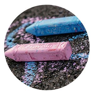 Pink and blue Crayola Chalk laying on black pavement with chalk lines