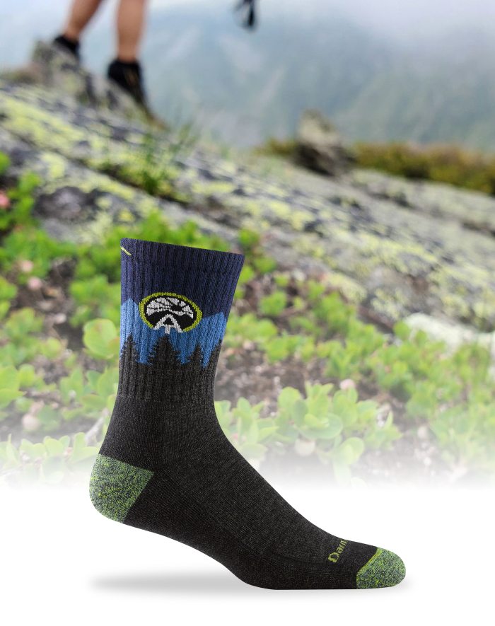 Support the ATC - our AT sock positioned in front of a rocky mossy summit trail