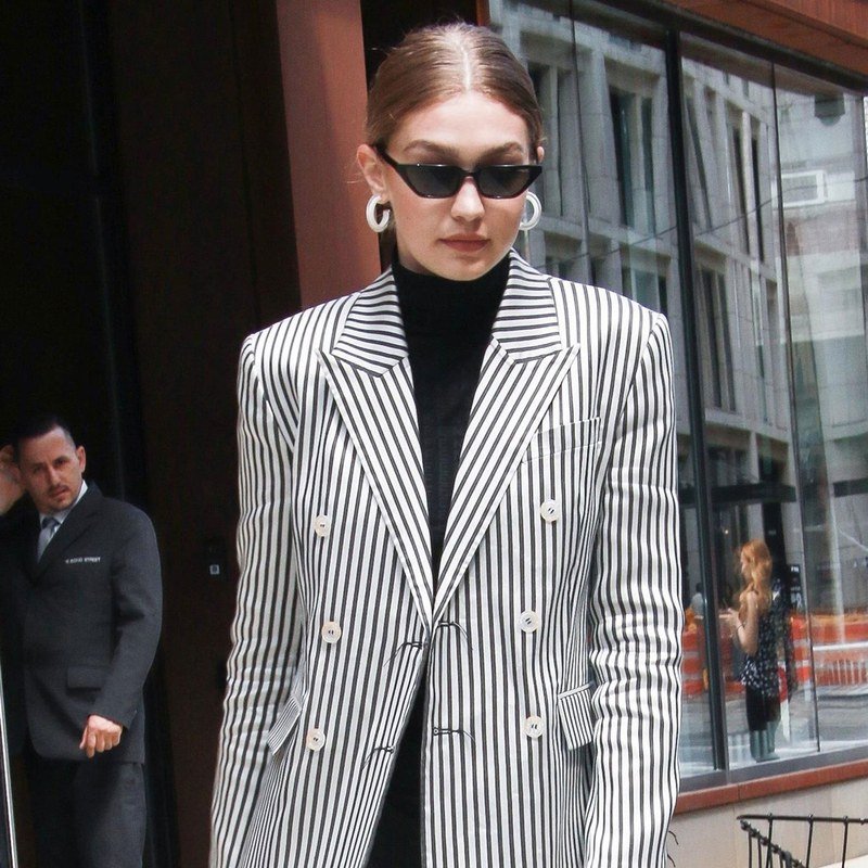 Gigi Hadid pairs a slicked knot with thin sunglasses.