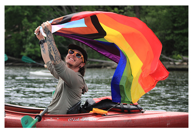Venture Out Project image of kayaker holding pride flag.