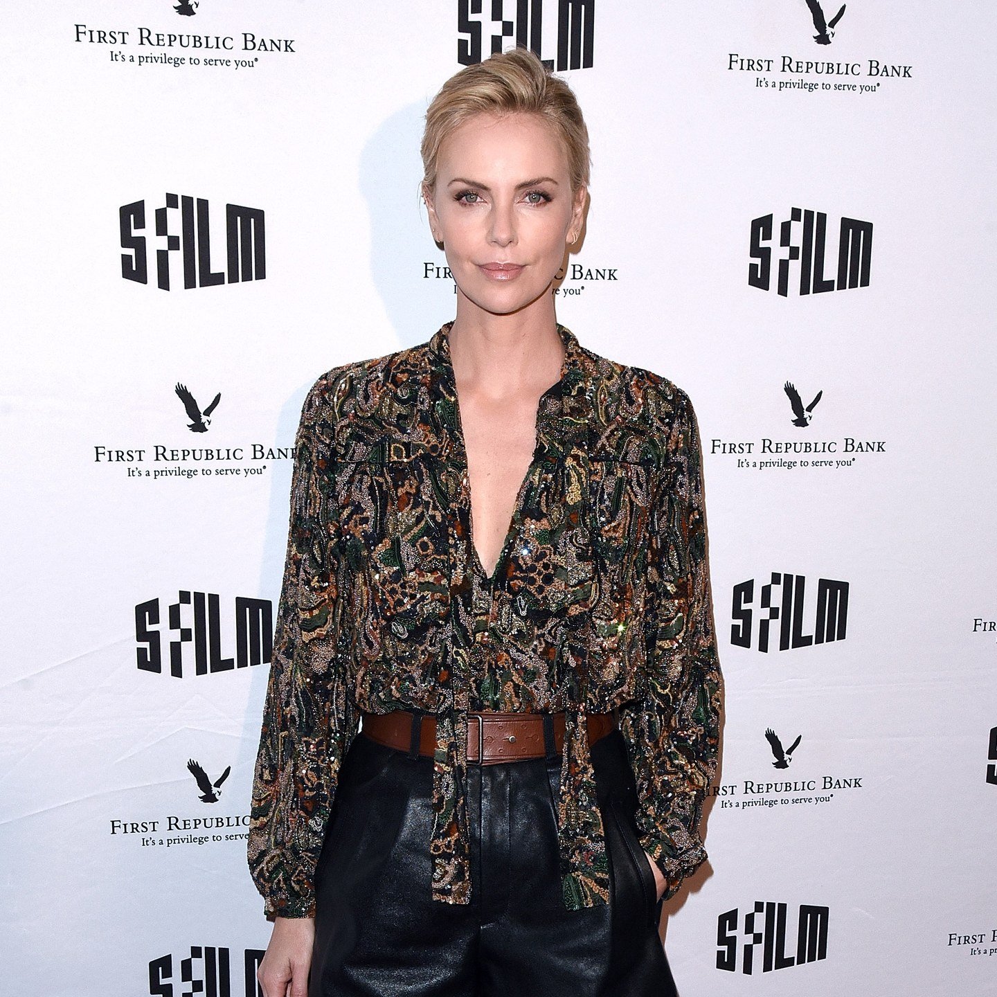 Charlize Theron pairs brushed-back blonde with a nude lip.