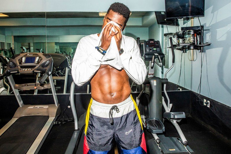 a fit man wiping sweat from his face with his shirt 